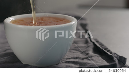 pour black tea in white cup closeup with copy space 64030064