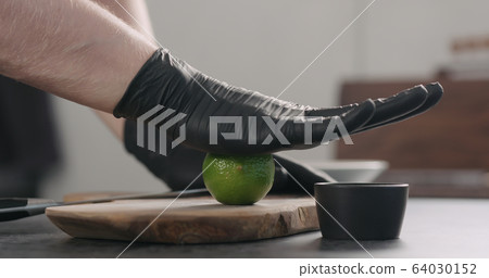 man hands in black gloves roll lime on olive wood board 64030152
