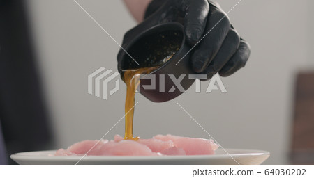man hands pour oil spices marinade over raw turkey fillet slices in white bowl man hands pour oil spices marinade over raw turkey fillet slices in white bowl 64030202