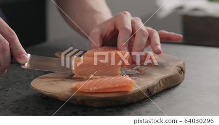 man hands slicing salted trout with knife on olive wood board man hands slicing salted trout with knife on olive wood board 64030296