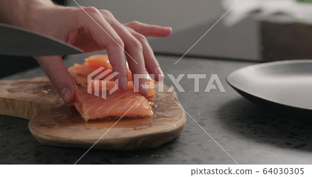 man hands chopping salted trout with knife on olive wood board 64030305