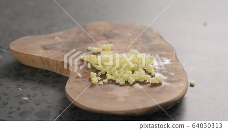 chopped fresh ginger root with knife on olive wood board 64030313