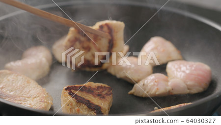 shot of frying turkey fillet pieces on nonstick pan and turning them with wood spatula shot of frying turkey fillet pieces on nonstick pan and turning them with wood spatula 64030327
