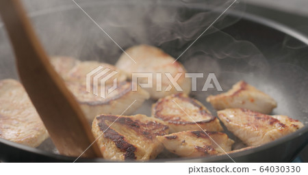 shot of frying turkey fillet pieces on nonstick pan and moving them with wood spatula shot of frying turkey fillet pieces on nonstick pan and moving them with wood spatula 64030330