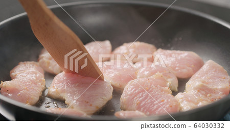 shot of frying turkey fillet pieces on nonstick pan and moving them with wood spatula shot of frying turkey fillet pieces on nonstick pan and moving them with wood spatula 64030332