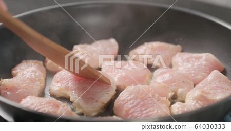 shot of frying turkey fillet pieces on nonstick pan and moving them with wood spatula shot of frying turkey fillet pieces on nonstick pan and moving them with wood spatula 64030333