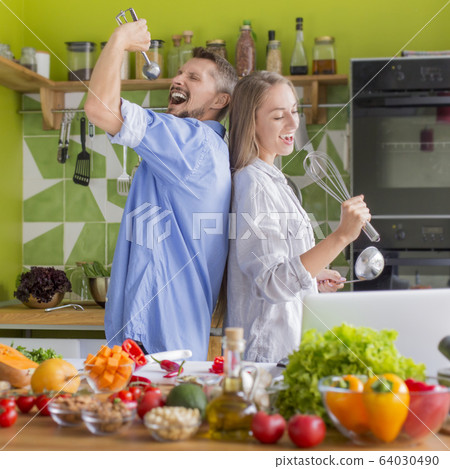 Young unrecognizable couple preparing healthy lunch and funny singing 64030490