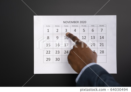 African man showing with finger on calendar date African man showing with finger on calendar date 64030494
