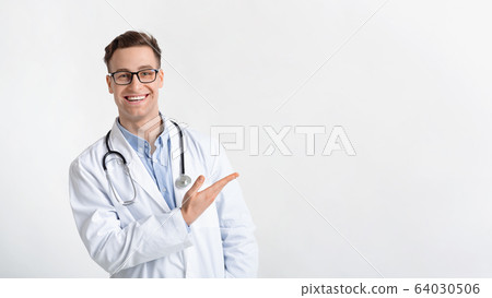 Smiling doctor in coat points to free place Smiling doctor in coat points to free place 64030506