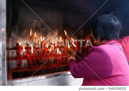 Woman light up her incense with candles Woman light up her incense with candles 64030630