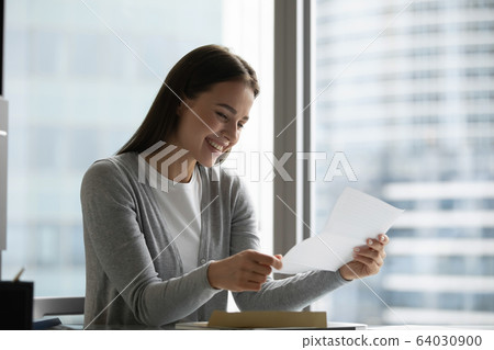 Smiling young woman get good news in postal correspondence 64030900