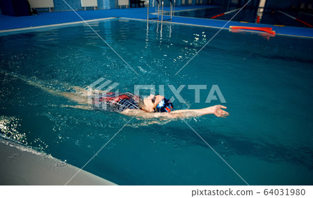 Female swimmer swimming on her back in pool Female swimmer swimming on her back in pool 64031980