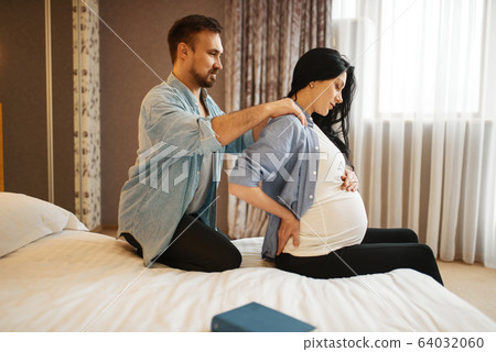 Husband doing massage to his pregnant wife at home Husband doing massage to his pregnant wife at home 64032060