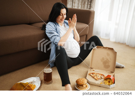 Pregnant woman smoking and eats unhealthy food Pregnant woman smoking and eats unhealthy food 64032064