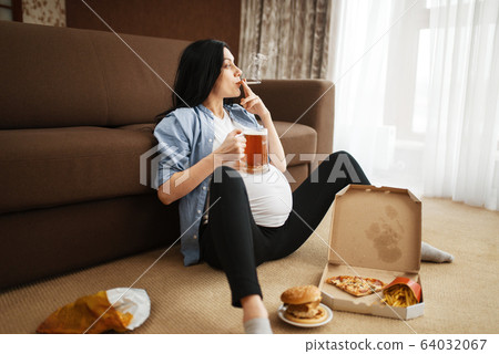 Pregnant woman with belly smoking and drinks beer Pregnant woman with belly smoking and drinks beer 64032067