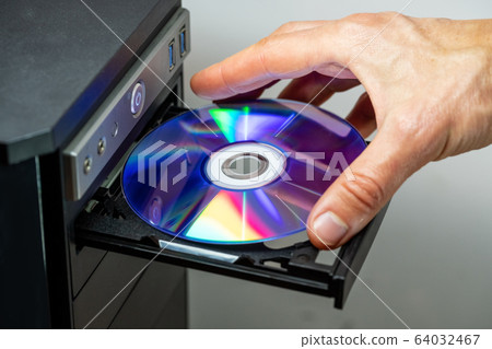 Hand inserting DVD into a computer. Closeup. Hand inserting DVD into a computer. Closeup. 64032467