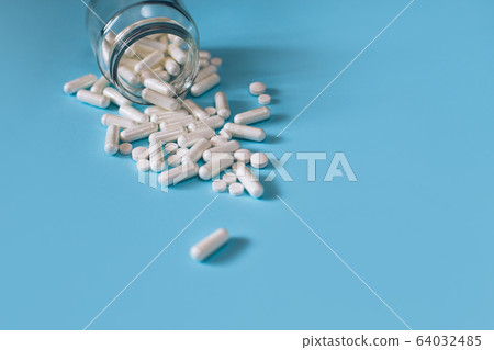 White medical pills on blue background. White medical pills on blue background. 64032485