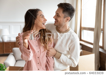 Happy homeowners cuddling, amazed by real estate purchase. 64033839
