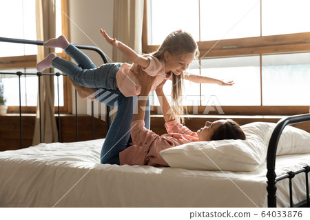 Healthy young mixed race mother lifting small preschool daughter. 64033876