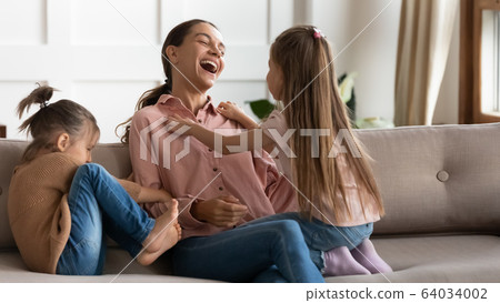 Happy young woman having fun with joyful small daughters. Happy young woman having fun with joyful small daughters. 64034002