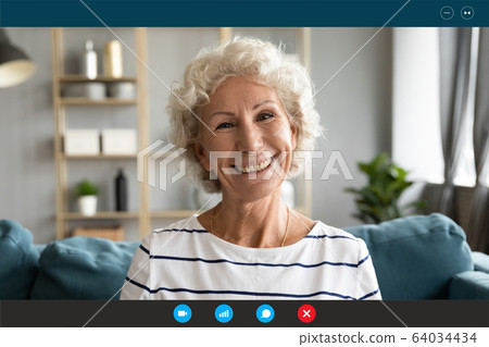 Grandmother having pleasant distant conversation by videoconference app at home 64034434
