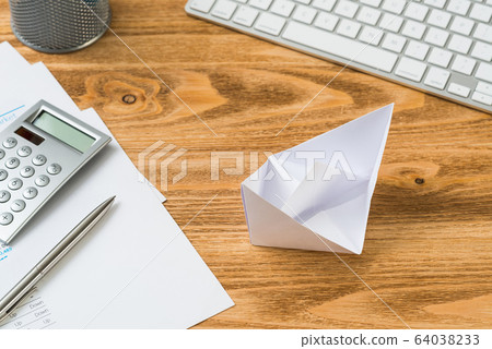 Wooden office desk with white origami boat. Wooden office desk with white origami boat. 64038233