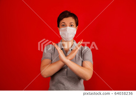 A woman in a mask indicates stopping the spread of the COVID-19 virus.. The concept of preventing A woman in a mask indicates stopping the spread of the COVID-19 virus.. The concept of preventing 64038236
