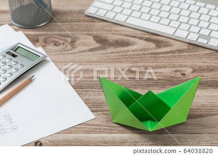 Top view office workspace with green paper ship Top view office workspace with green paper ship 64038820
