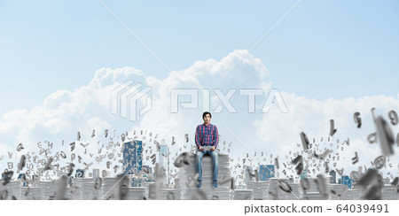 Attractive man sitting on pile of paper documents. 64039491