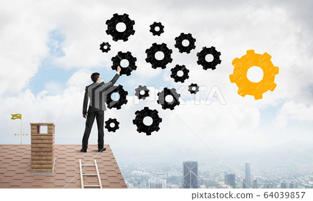 Businessman standing with back on house brick roof and drawing. Mixed media Businessman standing with back on house brick roof and drawing. Mixed media 64039857