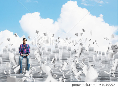 Attractive man sitting on pile of paper documents. 64039992