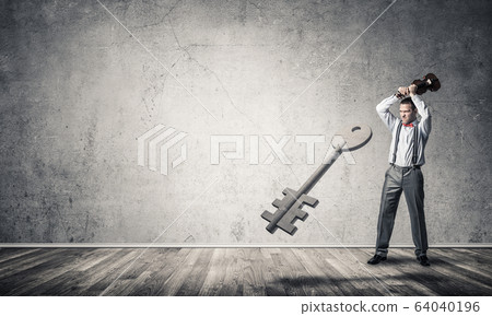 Breaking through access concept with man in room crashing concrete key Breaking through access concept with man in room crashing concrete key 64040196