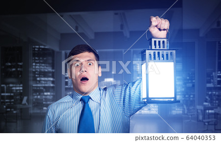 Horrified businessman holding glowing lantern 64040353