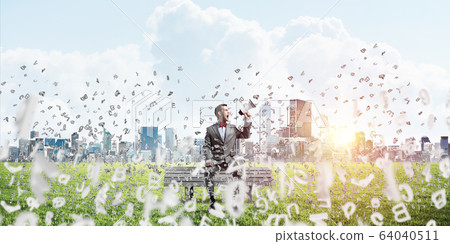 Businessman in summer park on bench announcing something in loudspeaker and symbols fly around Businessman in summer park on bench announcing something in loudspeaker and symbols fly around 64040511