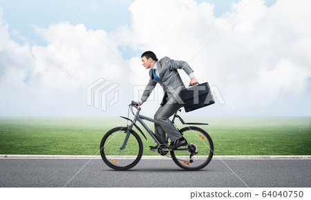 Young man riding bicycle on highway Young man riding bicycle on highway 64040750