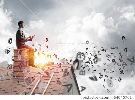 Man on brick roof working with smartphone and symbols flying around 64040761