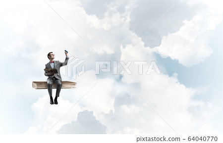 Young businessman or student floating in blue sky and studying the science 64040770