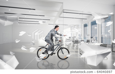 Businessman with paper documents in hand on bike 64040897