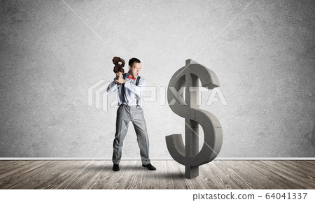 Determined banker man in empty concrete room breaking dollar figure Determined banker man in empty concrete room breaking dollar figure 64041337