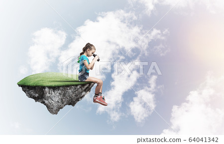 Concept of careless happy childhood with girl looking in binoculars Concept of careless happy childhood with girl looking in binoculars 64041342