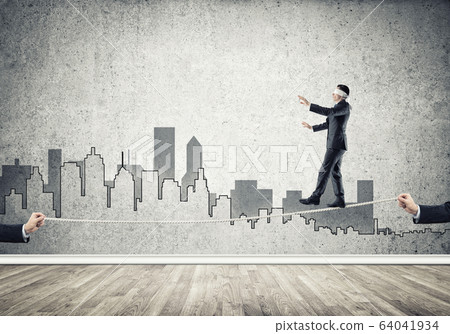 Business concept of risk support and assistance with man balancing on rope 64041934