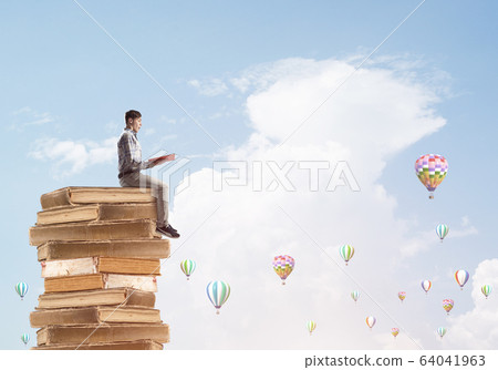 Man student on stack reading book and aerostats flying around Man student on stack reading book and aerostats flying around 64041963
