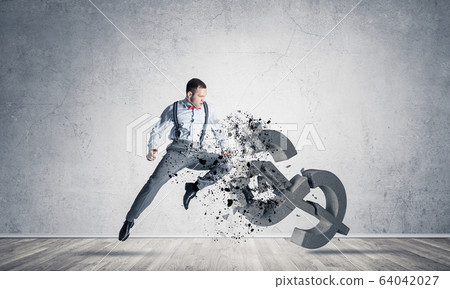 Determined banker man in empty concrete room breaking dollar fig Determined banker man in empty concrete room breaking dollar fig 64042027