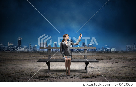 Business woman holding smartphone with raised hand Business woman holding smartphone with raised hand 64042060