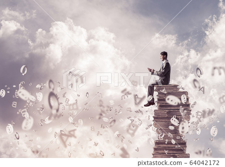 Businessman or student on book and symbols flying around Businessman or student on book and symbols flying around 64042172