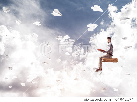 Handsome man student reading book and paper planes flying around Handsome man student reading book and paper planes flying around 64042174