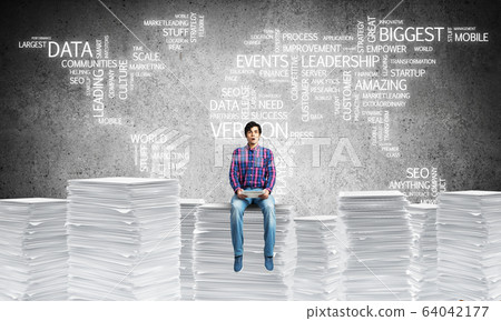 Attractive man sitting on pile of paper documents. Attractive man sitting on pile of paper documents. 64042177