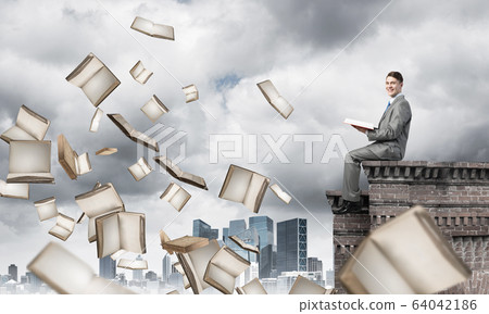 Man on roof reading book and many of them flying in air Man on roof reading book and many of them flying in air 64042186