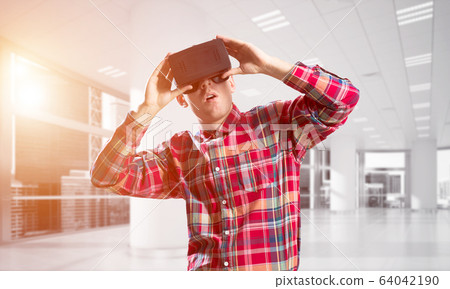 Concept of modern entertaining technologies with man wearing virtual reality mask Concept of modern entertaining technologies with man wearing virtual reality mask 64042190