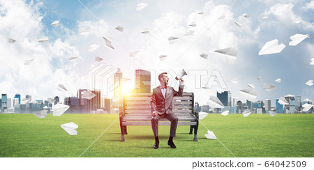 Businessman in summer park announcing something in loudspeaker and paper planes flying around 64042509